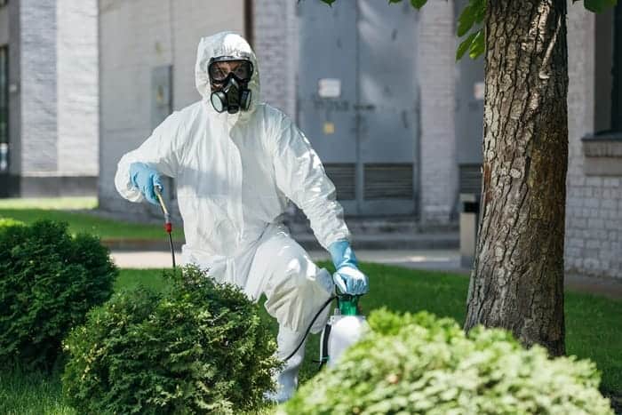Pest control technician applying treatment around a property